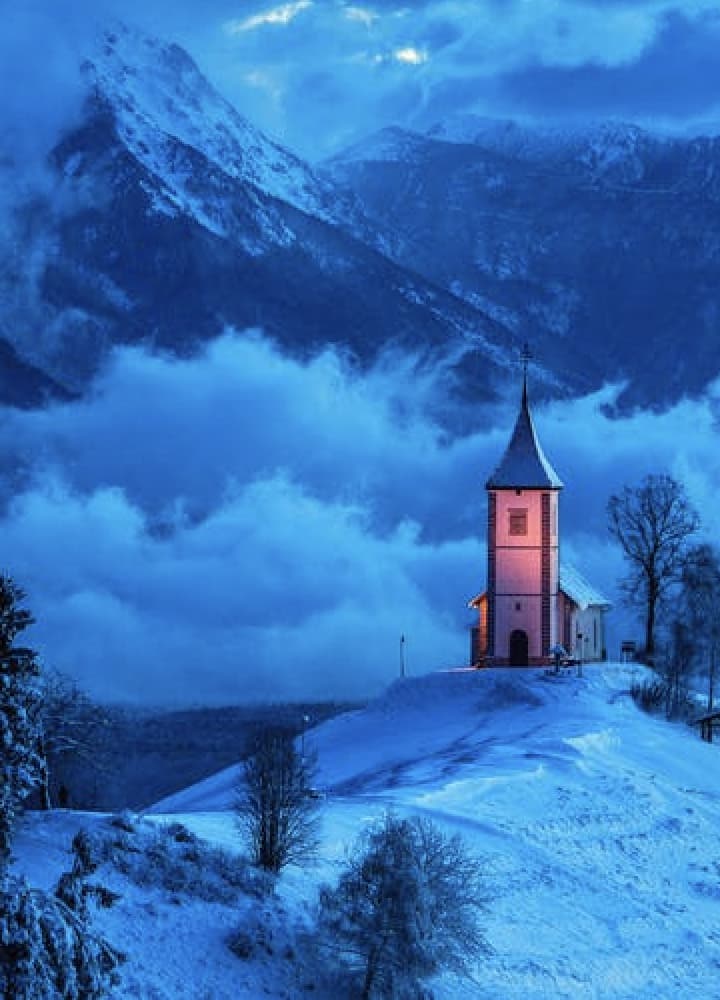 church on a hill in winter with mountains in the background