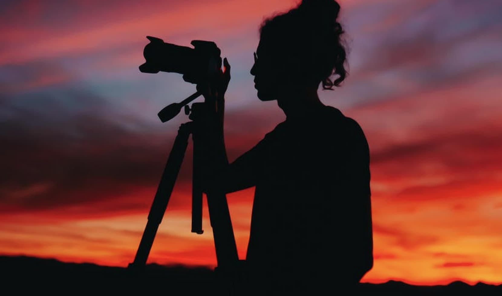 silhouette of a person taking a photo at dusk