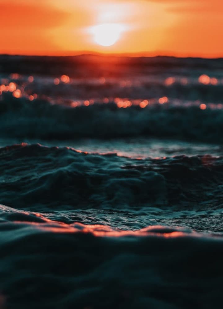 close up of waves in the shore line with the sun in the background setting