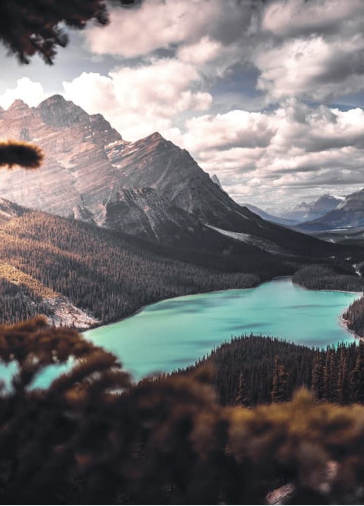 looking down a mountainous valley with a turkois color lake in the center